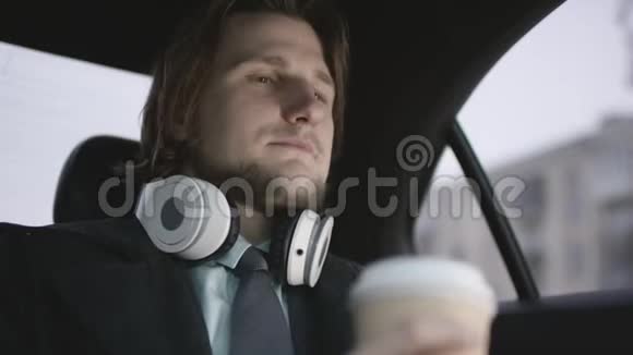 穿着开心果衬衫灰色西装戴着耳机喝着咖啡的英俊男子视频的预览图