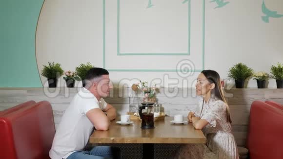 年轻人在咖啡馆的木桌上聊天喝茶视频的预览图