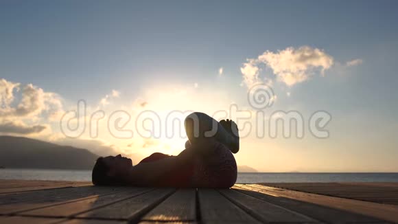 4K一名女子缓慢地在海边的木舟上练习普拉提视频的预览图