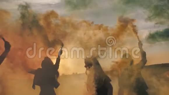 快乐的朋友在日落时挥舞着五颜六色的烟雾视频的预览图
