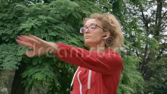 在春季或夏季多雨期间穿红色衣服和戴眼镜的积极健身妇女正在公园的户外活动视频的预览图