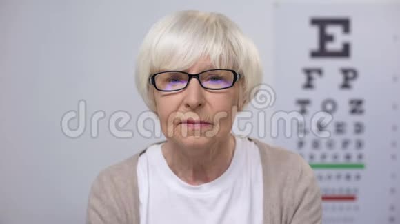 戴眼镜看报纸摇头白内障的老年妇女视频的预览图