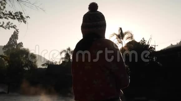 幸福美丽的年轻女子的剪影在日出的背景下在冬天寒冷的时候欣赏大自然的景色视频的预览图