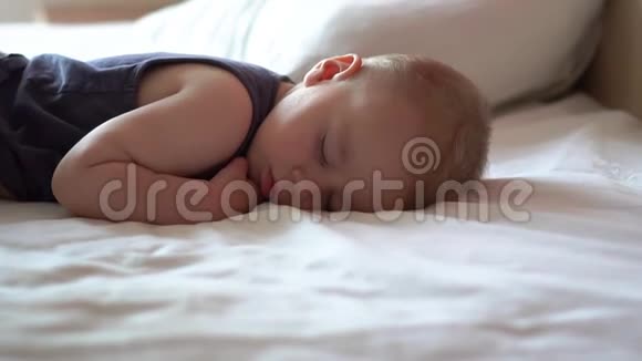 可爱的金发婴儿睡在一张大床上靠近一瓶牛奶慢动作视频的预览图