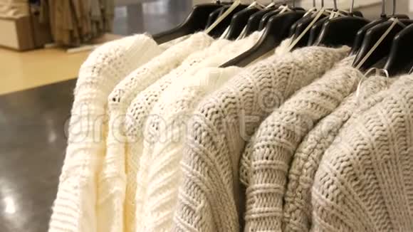 漂亮的女人服装店里衣架上的针织浅色毛衣视频的预览图