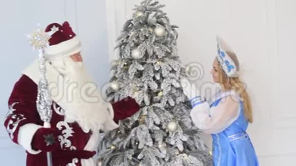 圣诞老人和雪少女在新年圣诞树附近带礼物视频的预览图
