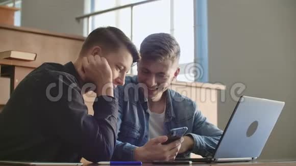 漂亮的女学生正在使用智能手机看屏幕有说有笑坐在大学的桌子上社会视频的预览图