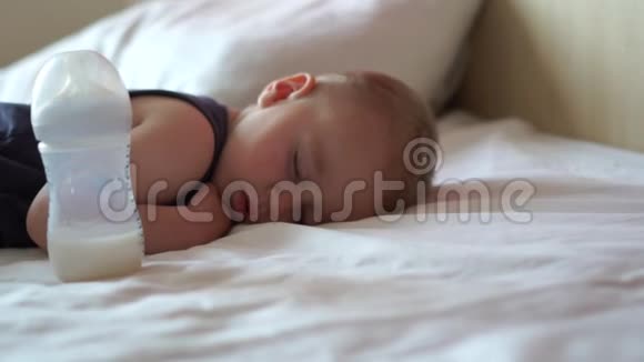 一个金发小男孩睡在一张大床上旁边是一牛奶慢动作着视频的预览图
