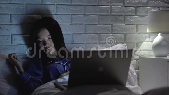 晚上睡在笔记本电脑前的女孩沉迷于网络社交网络视频的预览图