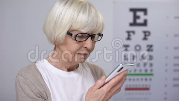 老年女性试图在智能手机上阅读字体小视力差视频的预览图