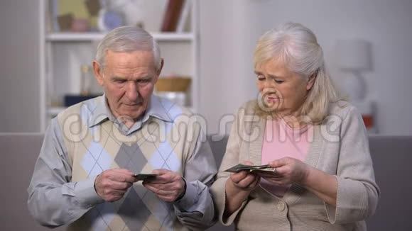 悲伤的老夫妇手里拿着几美元钞票没有足够的钱支付食物视频的预览图