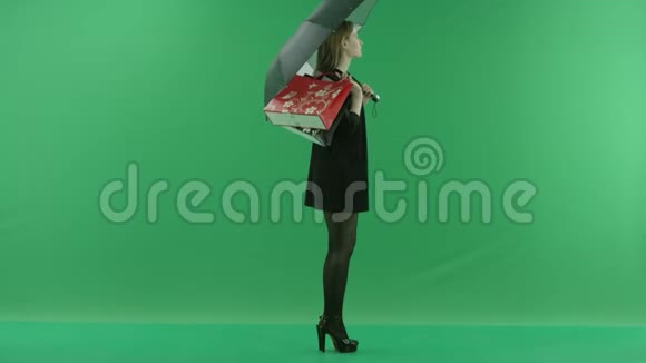 迷人的适合年轻女子在伞下她的肩膀上有袋子颜色关键绿色背景视频的预览图