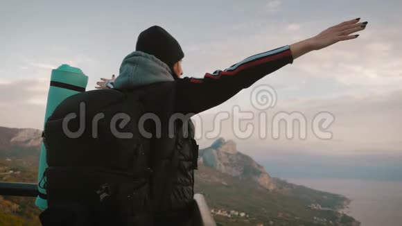 快乐的旅行家女孩用两只胳膊捂着头带着成功的情感欢呼成功的女徒步旅行者张开双臂视频的预览图