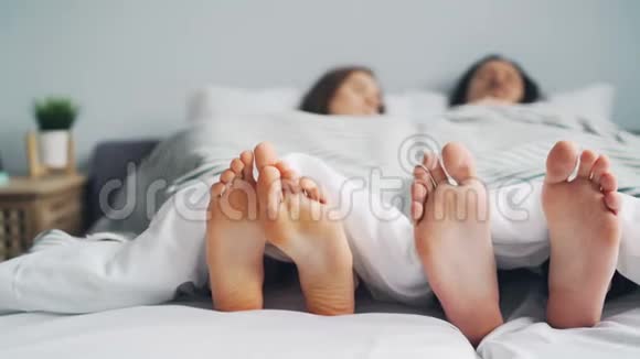 女孩和男孩一对在床上打盹光着脚躺在毯子下视频的预览图