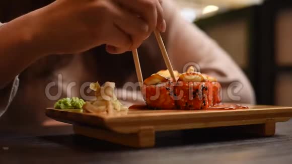 一个女孩坐在咖啡馆里在中国或日本餐馆里有面包卷和寿司有筷子的漂亮女人吃烤卷视频的预览图