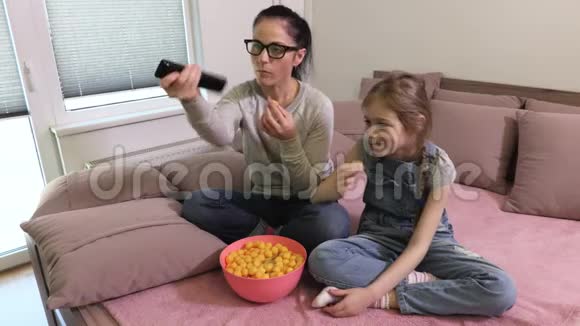 女儿和母亲在电视旁聊天吃薯片视频的预览图