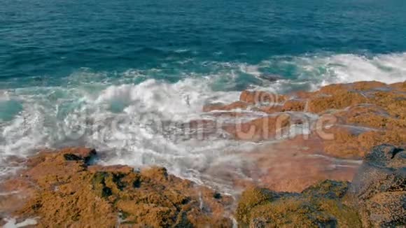 蓝色的海浪拍打着海岸的黄色石头大量白色泡沫和喷雾形式近点视频的预览图