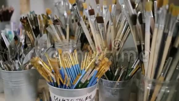 许多有艺术画笔的杯子站在艺术工作室的桌子上淘洗视频的预览图