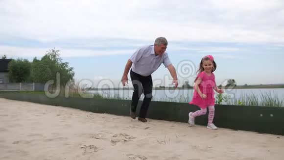 祖父赶上了她的孙女一家人在海滩上玩他们跑到镜头前4K慢慢视频的预览图
