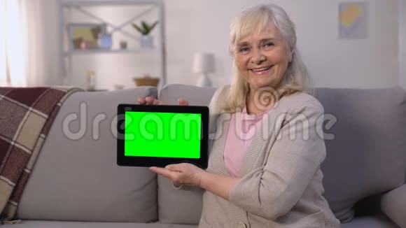 微笑成熟的女士手里拿着绿色屏幕平板电脑轻松银行购物视频的预览图
