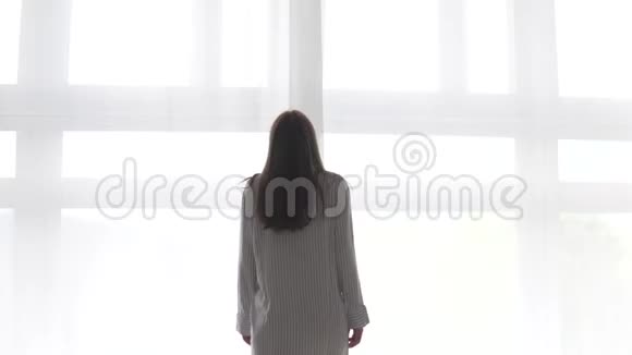 一个女人走到窗前打开白色的窗帘视频的预览图