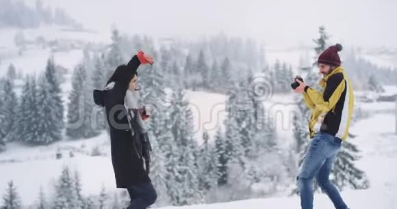 两个朋友高兴地来到了令人惊奇的地方小伙子在冬天的一个美丽的地方给他的朋友拍照视频的预览图