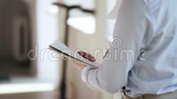 后景特写商人穿白色正式衬衫拿着纸记事本在现代轻办公职场写作视频的预览图