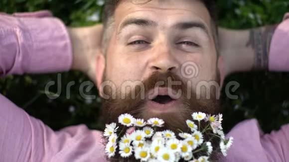 一个蓄着花的人躺在绿草上人脸上留着花胡子上留着天然的底色视频的预览图
