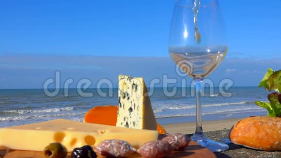 白葡萄酒倒入奶酪旁边的玻璃杯中视频的预览图