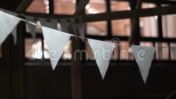 悬挂在户外的绳子上的白色三角旗傍晚在风中摇曳视频的预览图