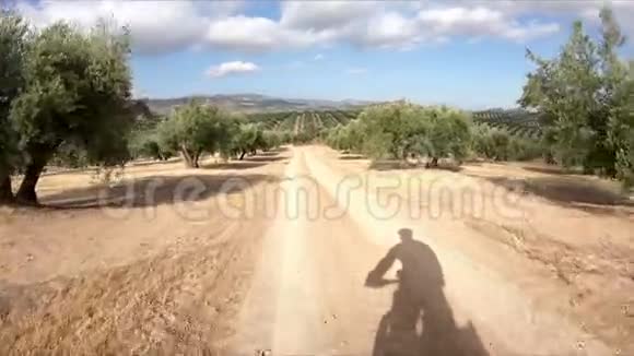 在阿尔卡迪特旁边的乡村小路上骑自行车的人的影子视频的预览图