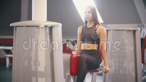 一位在健身房进行长发训练的运动员女子在蝴蝶训练装置上锻炼视频的预览图