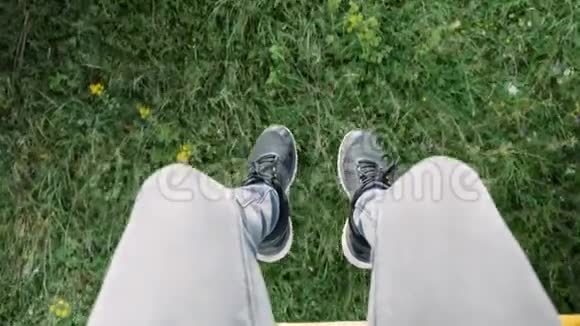 男子双脚穿黑色运动鞋坐在椅子上从山上穿过穿过绿草和鲜花俯视着山顶视频的预览图