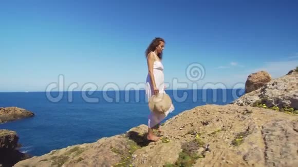 女孩赤着脚走上悬崖迎着蔚蓝的大海视频的预览图