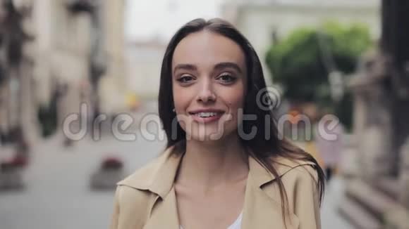 一幅美丽的年轻女孩看着幸福和满意的微笑和笑声站在城市背景特写视频的预览图