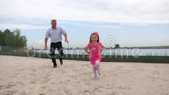孙女和祖父正沿着海滩跑步他们微笑着玩得开心4K慢慢视频的预览图