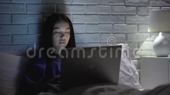 极度疲劳的亚洲女人晚上在卧室里工作工作狂视频的预览图