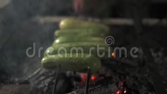 特写厨师双手翻烧烤西葫芦和搅拌燃烧的煤视频的预览图
