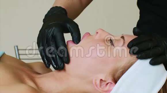 按摩治疗师正在水疗沙龙做女人下巴面部按摩视频的预览图