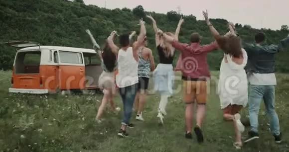 跑着一群时髦的朋友在球场中间后面是一辆复古的橙色面包车视频的预览图