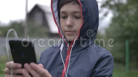 带耳机的男孩在户外通过电话听音乐关门视频的预览图