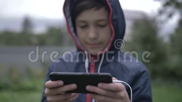 头罩里的男孩用电话玩游戏关门视频的预览图