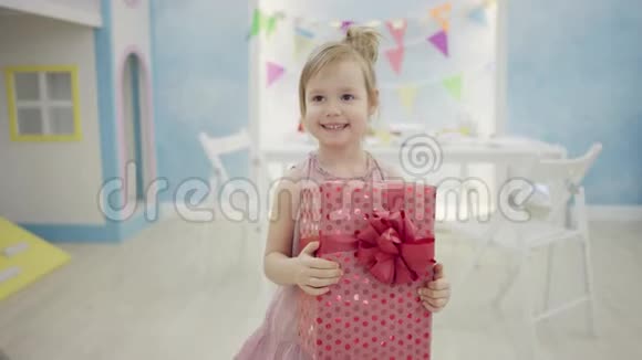 手里拿着生日礼物盒的小女孩在镜头前说话视频的预览图