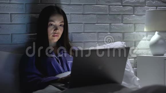 女人躺在床上匆忙地用笔记本电脑工作试图赶上最后期限加班加点视频的预览图
