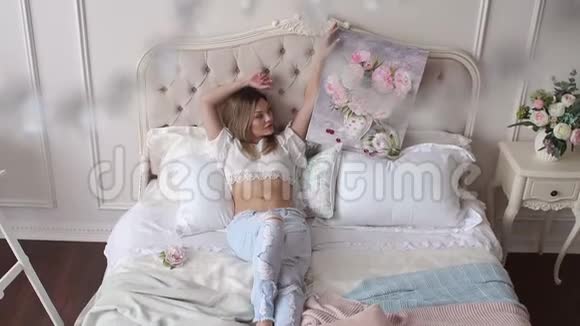 性感的女孩躺在床上手里拿着一张画着花的照片视频的预览图