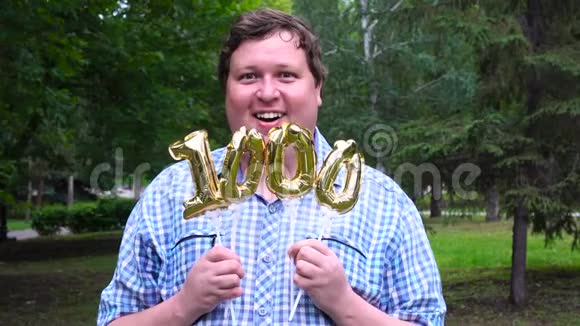 大个子拿着金色气球在户外做1000个数字十周年庆典晚会视频的预览图