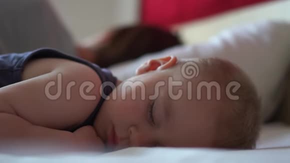 白天妈妈和蹒跚学步的孩子在床上慢慢地睡得香甜视频的预览图