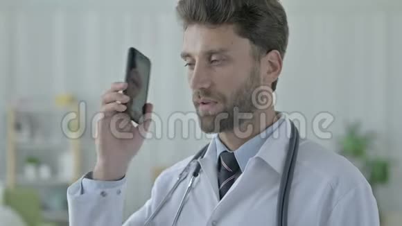 野心勃勃的年轻医生用手机说话视频的预览图