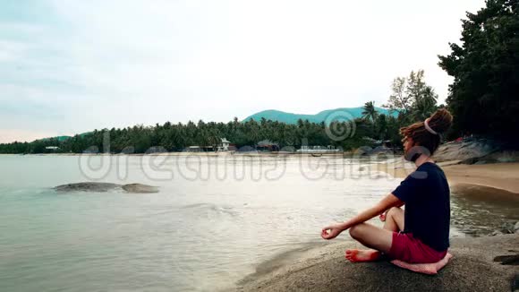 一个人坐在海边的石头上沉思带着恐惧症的莲花男视频的预览图