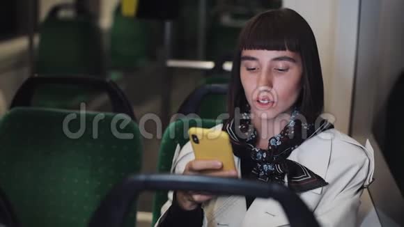 有魅力的年轻女性在电车上使用智能手机与朋友聊天慢动作因特网技术运输视频的预览图